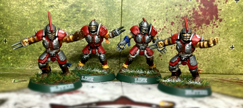 Two human blitzers and linement from the Blood Bowl team in gray and red.