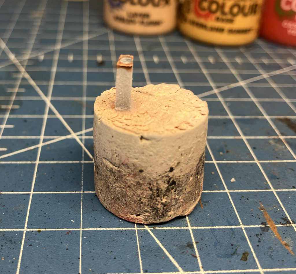 A piece of plastic secured onto a cork for easy miniature head painting.