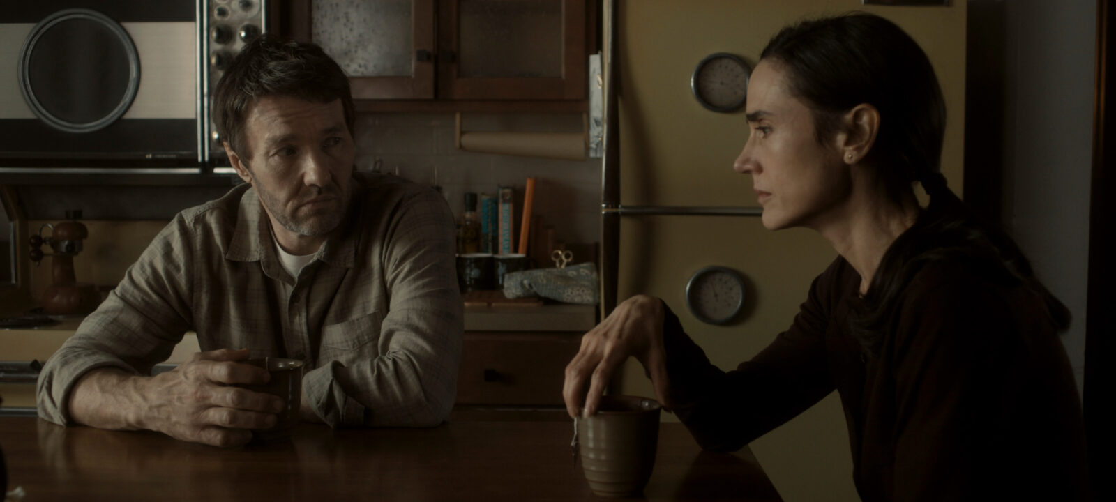 Jason and Daniella sit at their kitchen table in 1970's world in Dark Matter